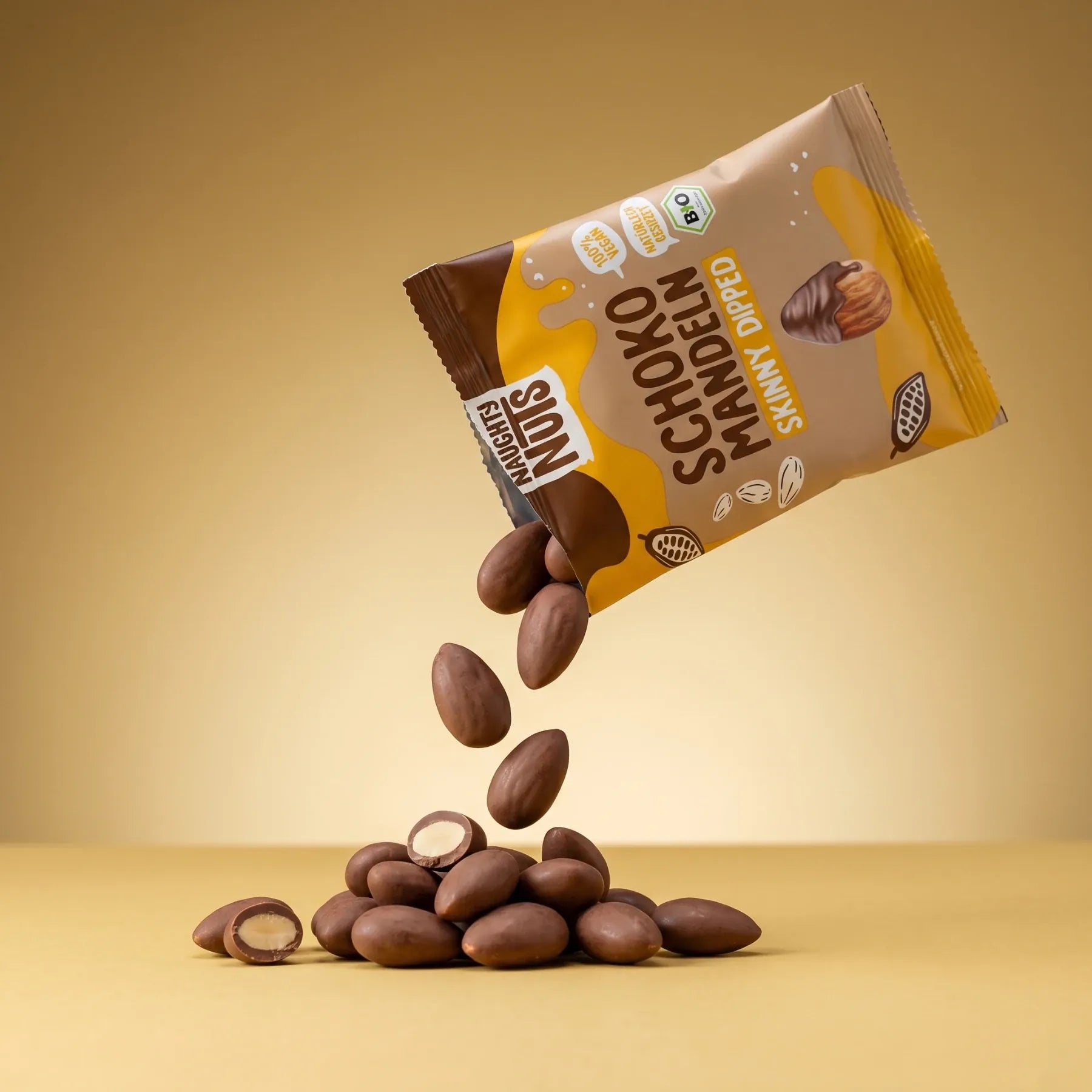 Bio Schoko-Mandeln (skinny dipped) fallen aus der Verpackung auf einen Haufen