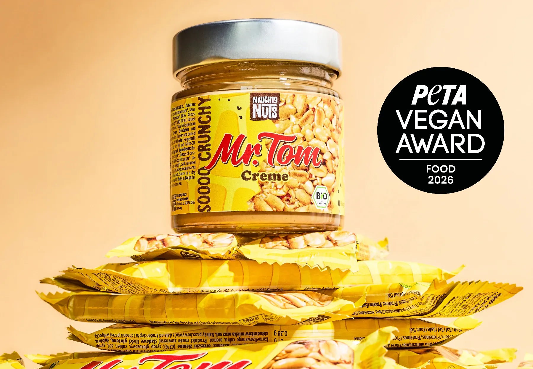 Mr Tom Erdnusscreme Glas auf einem Stapel Mr Tom Riegel mit PETA Vegan Award Logo